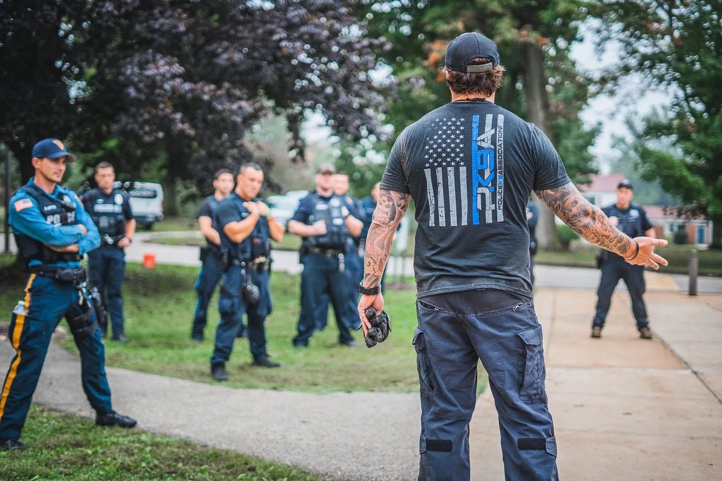 An instructor addresses police K9 handlers outdoors.
