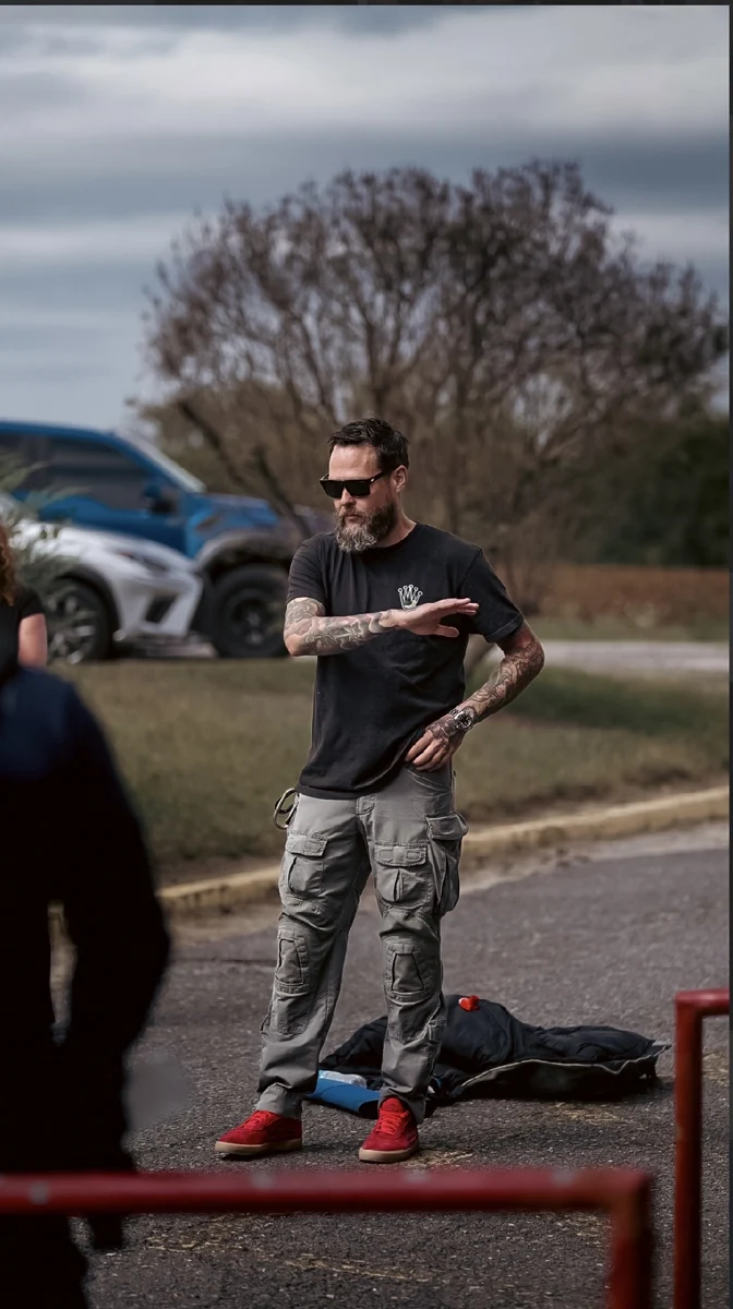 Ted Summers giving instruction outdoors beside a red training barrier.